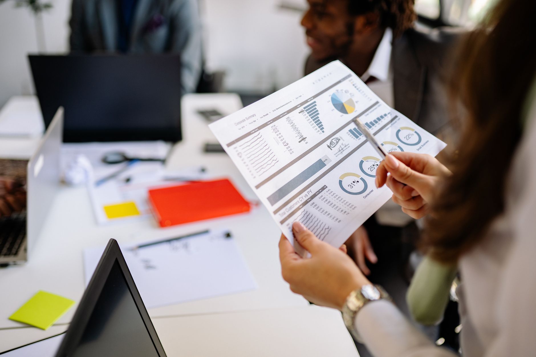 A manager holds a printed report of charts and figures during a team meeting at a conference table